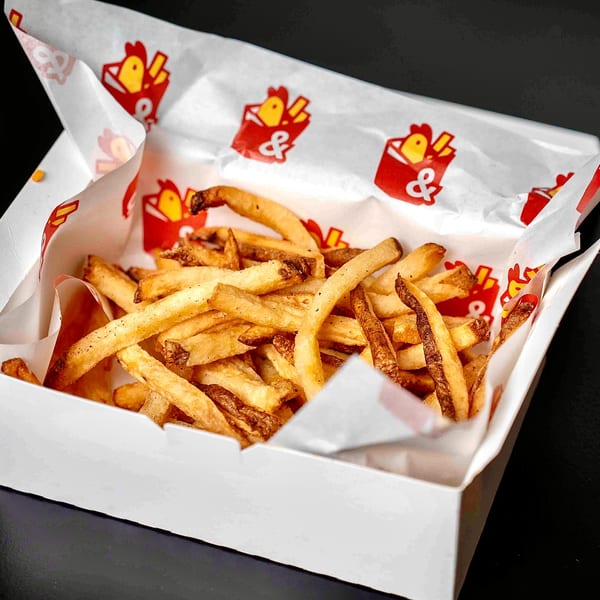 Golden-brown Box & Bird french fries in a white box with branded red and yellow paper lining.